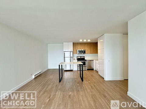 A spacious room with a dining table and chairs in the foreground and a kitchen area in the background.