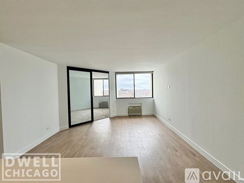 A spacious room with wooden floors and a large window overlooking a cityscape.