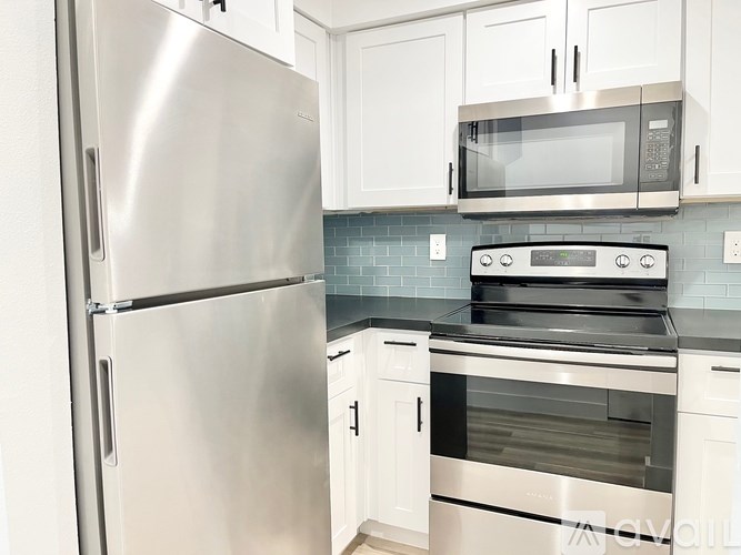 A kitchen with a stainless steel refrigerator, microwave, and oven.