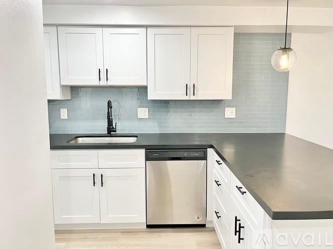 A kitchen with white cabinets and a black dishwasher.