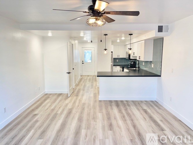 A spacious room with a ceiling fan and lighting fixtures.