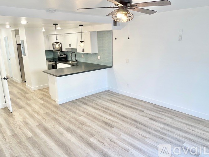 A kitchen with a fan and wooden flooring.