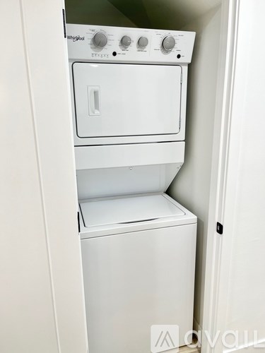 A white washing machine and dryer are stacked in a small space.