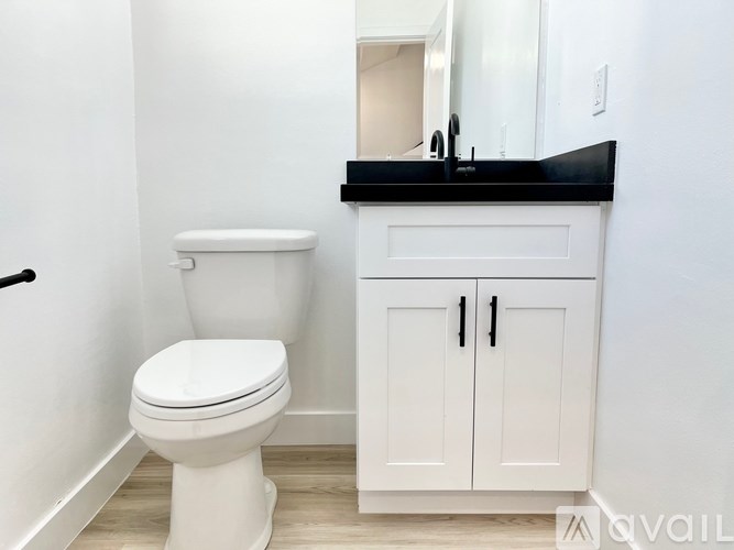 A white toilet sits next to a white cabinet with a black countertop.