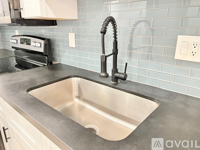 A kitchen with a stove, sink, and a tile backsplash.