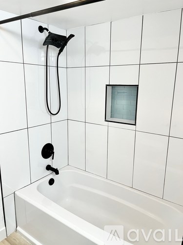 A white bathroom with a tub and a shower head.