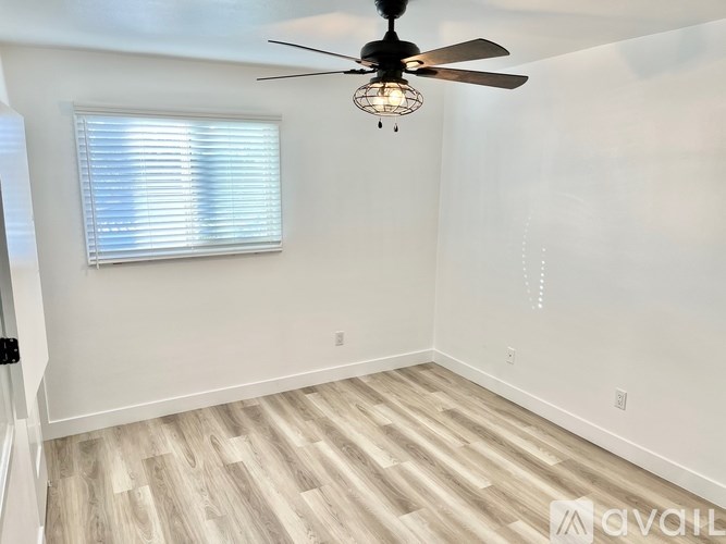 A room with a ceiling fan and a window with blinds.