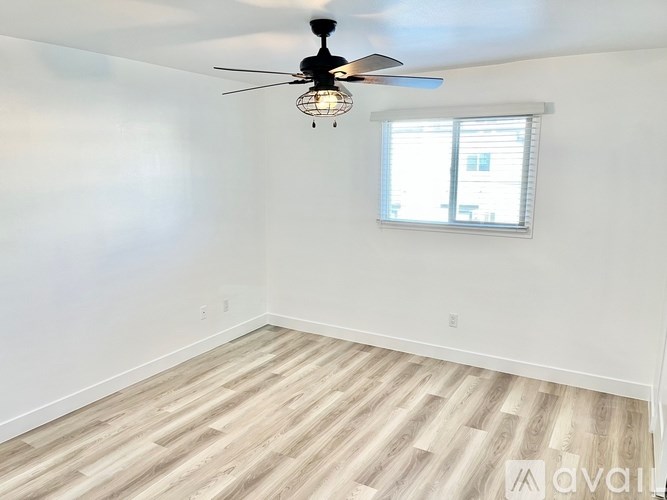 A room with a ceiling fan and a window with blinds.