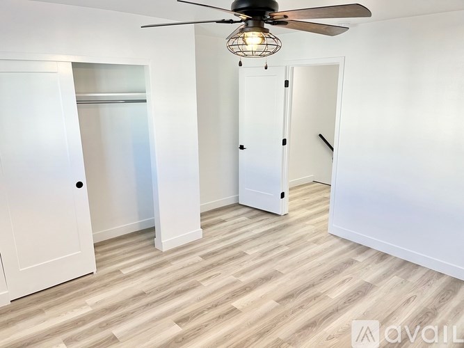 A room with a ceiling fan and wooden flooring.