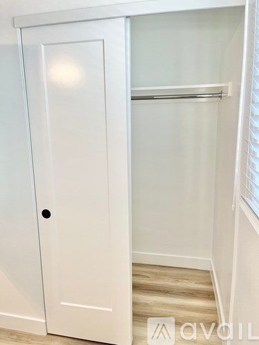 A white closet with a door and a shelf.