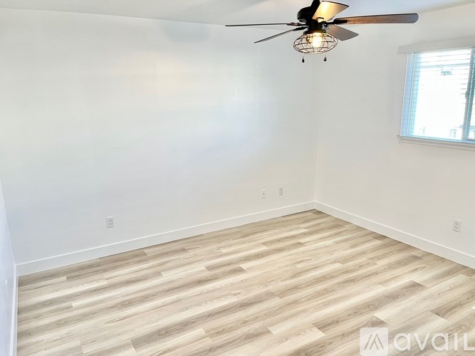 A room with a ceiling fan and wooden flooring.