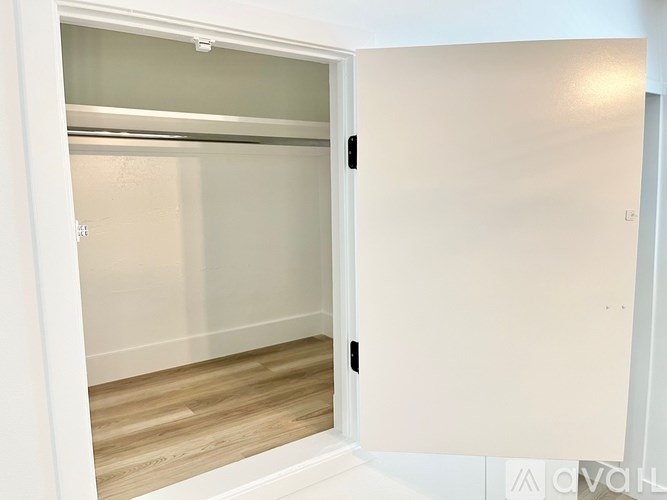 A white door is open to a room with a wooden floor.