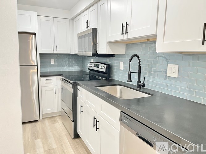A kitchen with white cabinets and a black countertop.