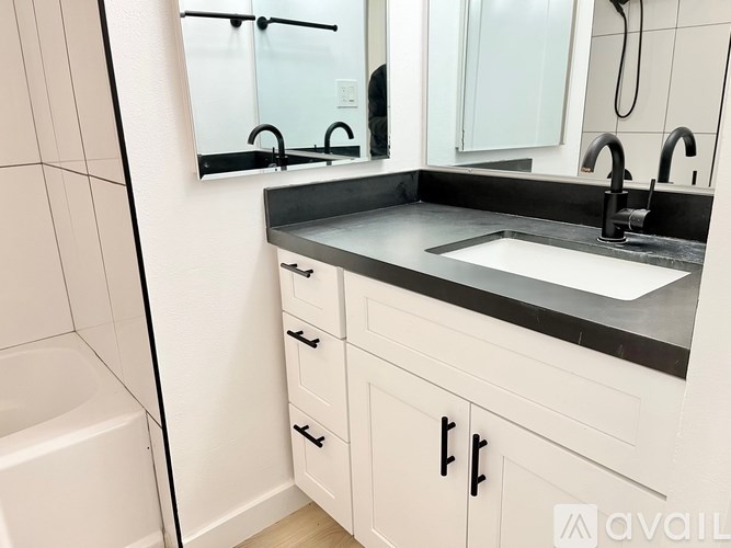 A bathroom with a white tub, sink, and cabinets.