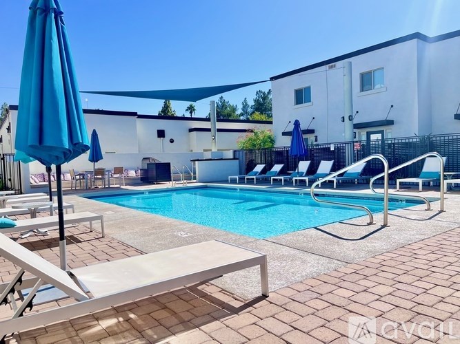 A pool with a blue umbrella and lounge chairs.