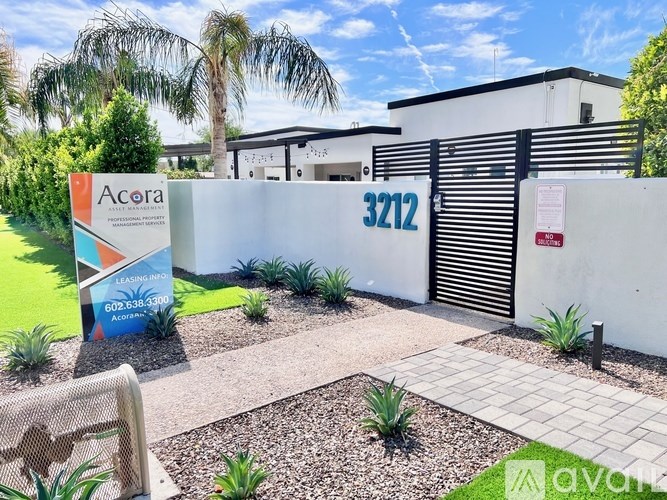 The image shows a well-maintained garden in front of a building with a sign that reads "Acora".