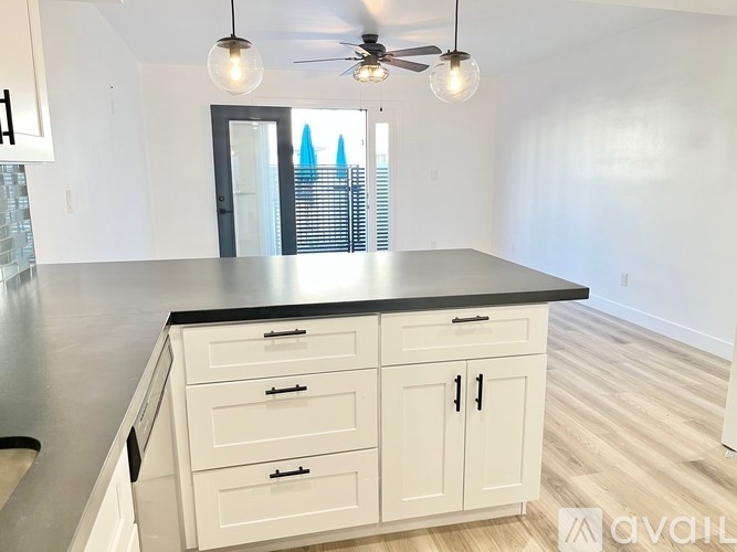 A kitchen with white cabinets and a black countertop.