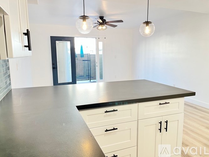 A kitchen with a black countertop and white cabinets.