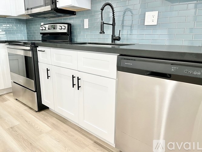A kitchen with white cabinets and a black countertop.