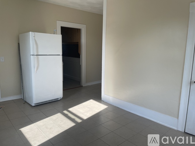 A white refrigerator is in a room with a door open.
