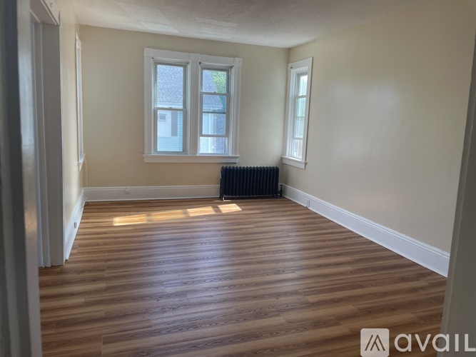A room with wooden flooring and two windows.