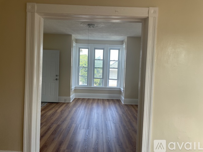 A room with wooden floors and a window overlooking a garden.