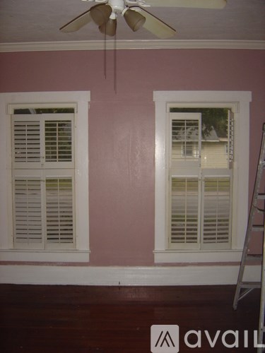 A room with a pink wall and a fan on the ceiling.