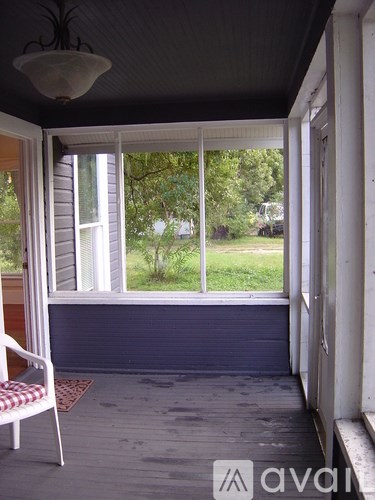 A room with a chair and a window overlooking a green area.