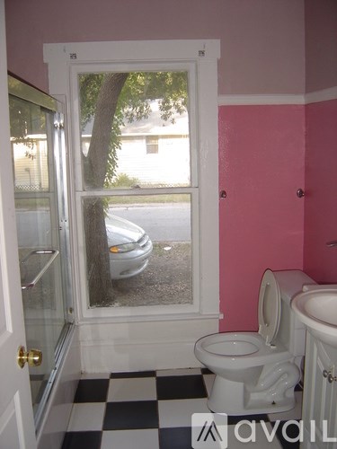 A white toilet in a room with pink walls.