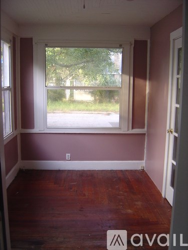 A room with a window and wooden floors.