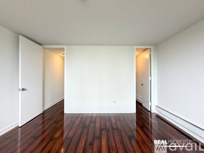 A spacious room with a wooden floor and a cabinet in the corner.
