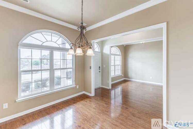 A well-lit room with a chandelier and a large arched window.