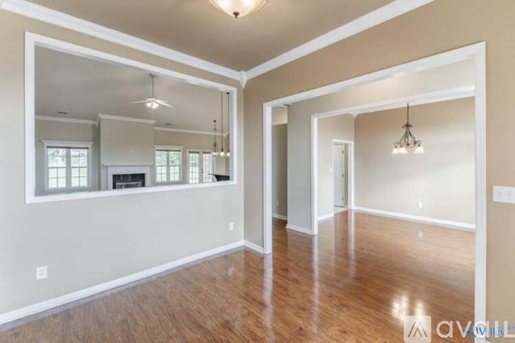 A large empty room with wooden floors and a mirror on the wall.