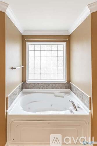A white bathtub with a window above it.