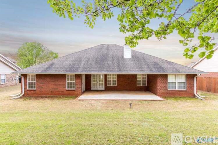 A house with a brick facade and a grey roof is surrounded by a grassy yard.