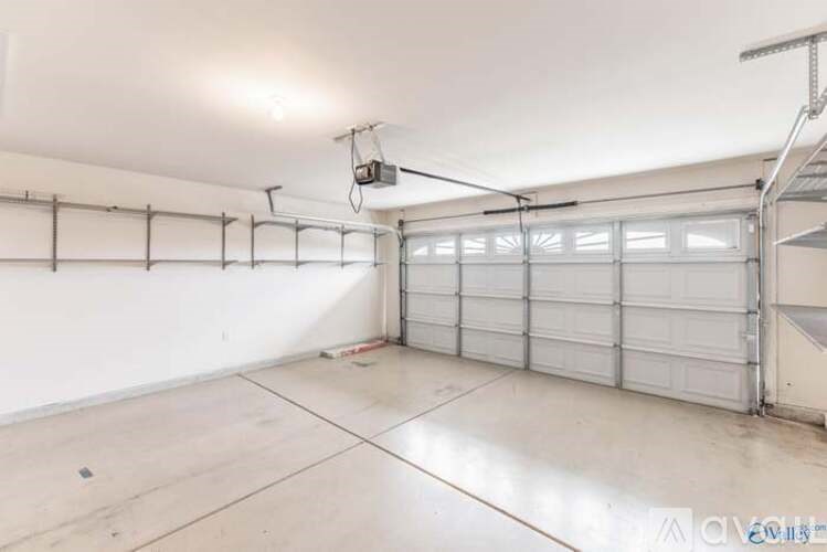 A spacious garage with a white wall and a closed white garage door.