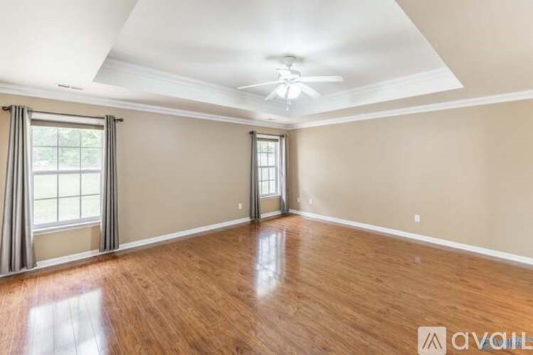 A spacious room with wooden floors and a ceiling fan.