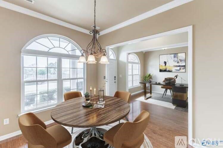 A dining room with a round wooden table surrounded by chairs.