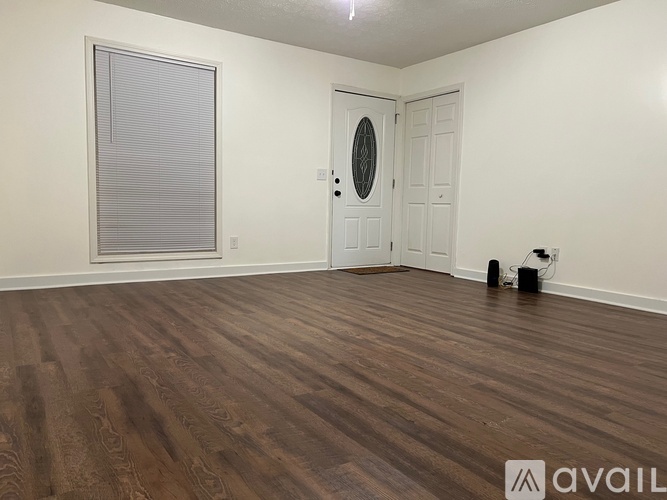 A room with wooden flooring and a white door with a round mirror above it.