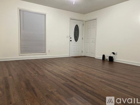 A room with wooden flooring and a white door with a round mirror above it.