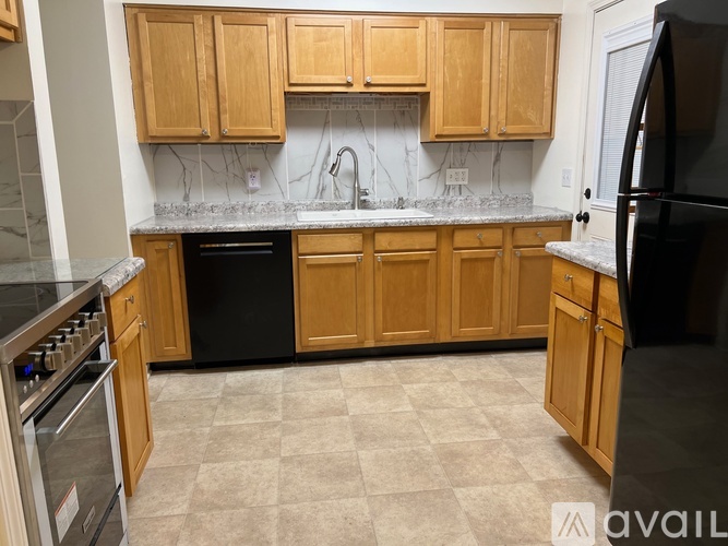 A kitchen with wooden cabinets and a black refrigerator.