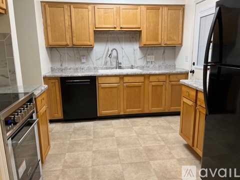 A kitchen with wooden cabinets and a black refrigerator.