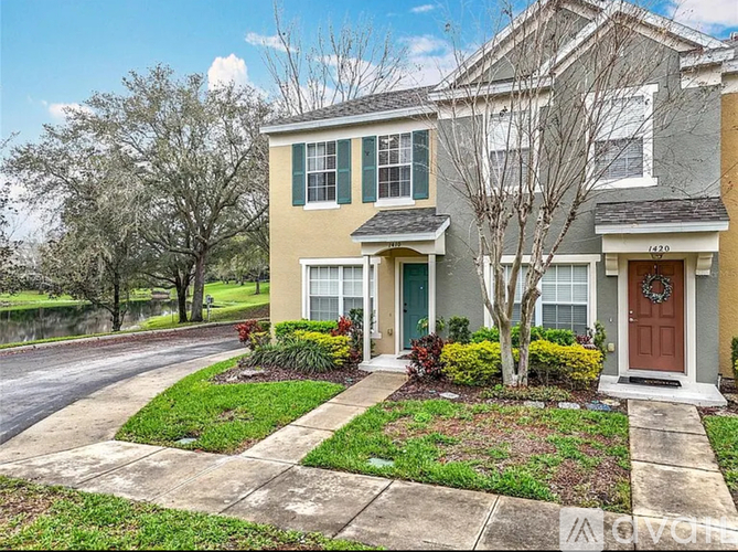 A two-story house with a front yard and a tree.