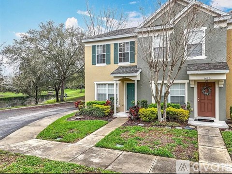 A two-story house with a front yard and a tree.