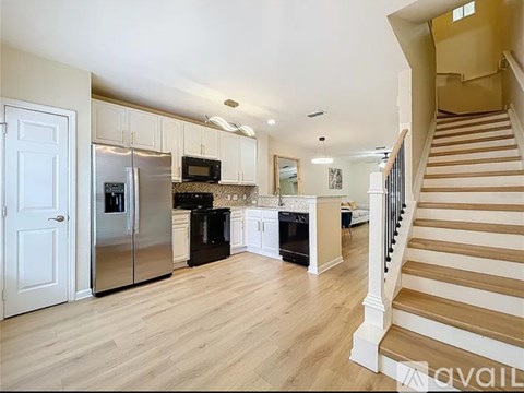 A kitchen with a refrigerator, microwave, oven, and sink.