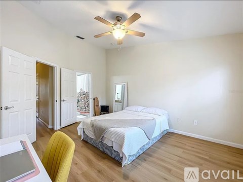 A bedroom with a bed, a chair, and a ceiling fan.