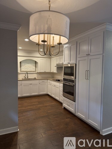 A kitchen with white cabinets and a chandelier.