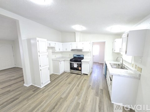 A kitchen with white cabinets and a wood floor.