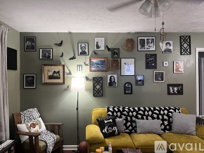 A living room with a yellow couch and a wall full of pictures.