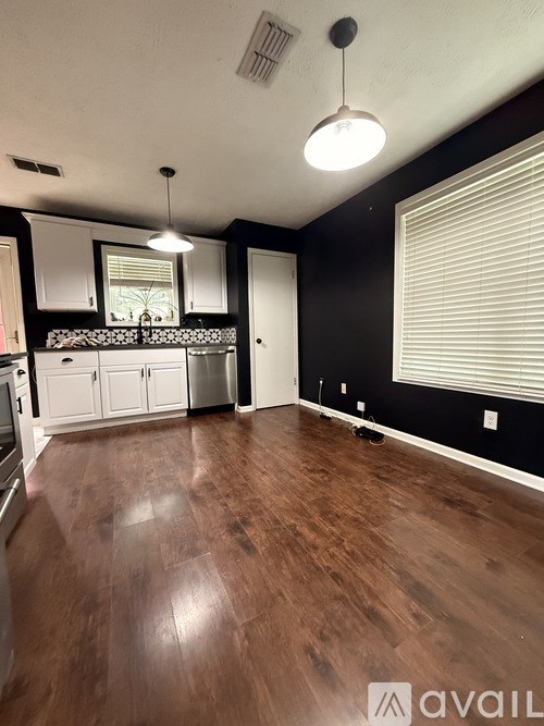 A kitchen with wooden floors and white cabinets.